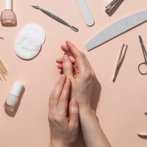 Natural nail care tools and manicure products arranged around healthy hands on a soft background
