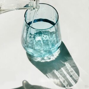 Glass of fresh drinking water being poured in sunlight representing hydration and healthy lifestyle habits for belly fat loss